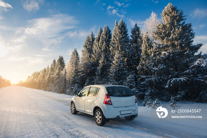 Car on a winter road through a snow covered forest.