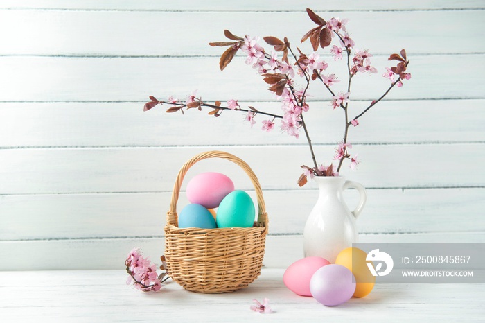 Easter eggs in a basket and pink cherry blossoms, Easter greeting card, wooden background