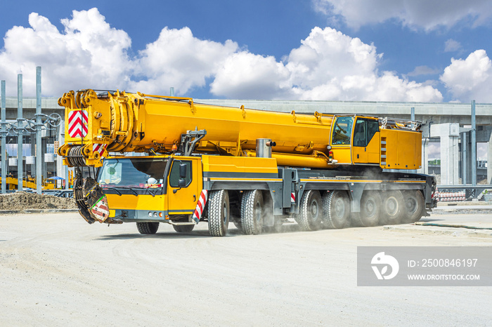 mobile crane against deep blue sky and white clouds.