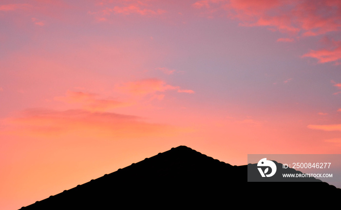 silhouette of roof on a new house with pink fantasy sky before sunset