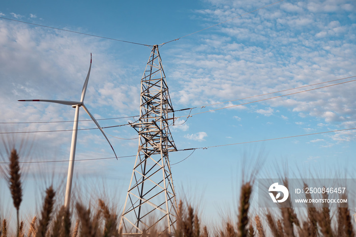 Windmill produces renewable energy. Wind turbine generates clean energy for supporting power transmission lines against tower under blue sky