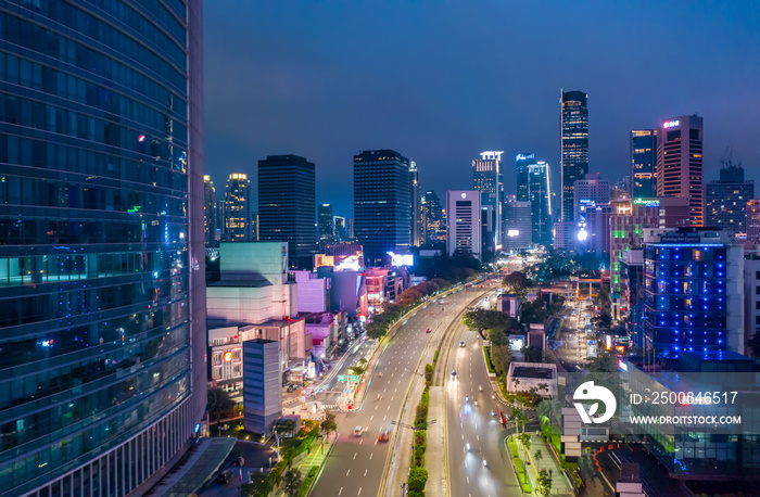 Aerial night view of fast moving traffic on the multi lane highway through urban city center with skyscrapers Highway through downtown Jakarta, Indonesia