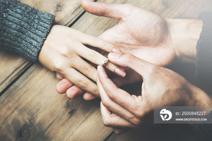 Young man makes woman marriage proposal and puts an engagement ring on her finger