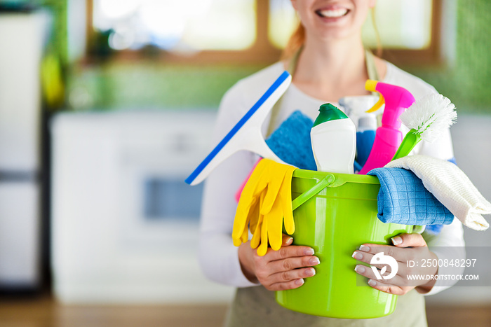 Woman holding cleaning items in plastic bucket. Kitchen service washing concept.