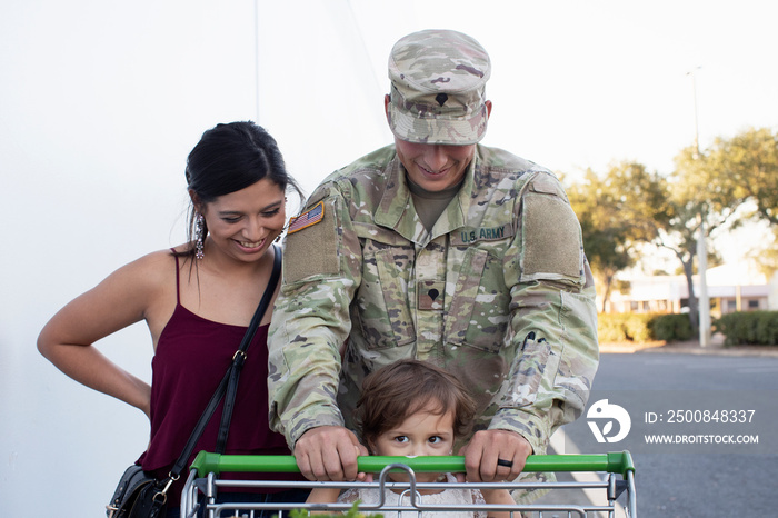 Soldier helping his daughter push a shopping cart