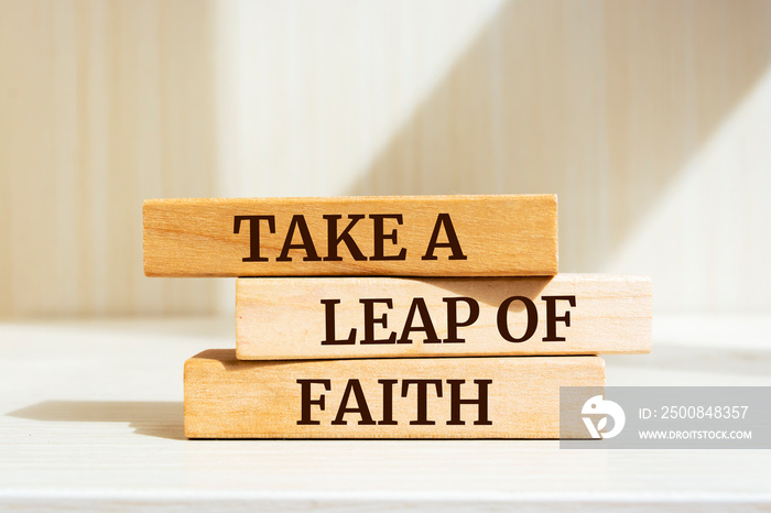 Wooden blocks with words ’TAKE A LEAP OF FAITH’.