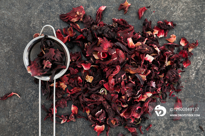 Heap of dry hibiscus tea with sieve on grey background