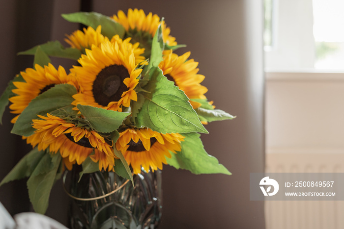 A bouquet of sunflowers in a vase by the window.