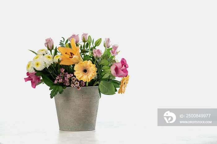 Bouquet of different flowers in metall bucket on white background