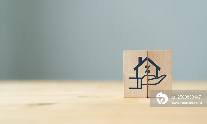 Home loan, mortgage and buy a real estate concept. The wooden cube with icon of hands holding house model in grey background and copy space. Banner for home buying, loan and insurance