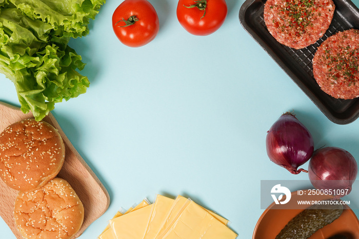 Homemade burger ingredients on blue table background with copy space