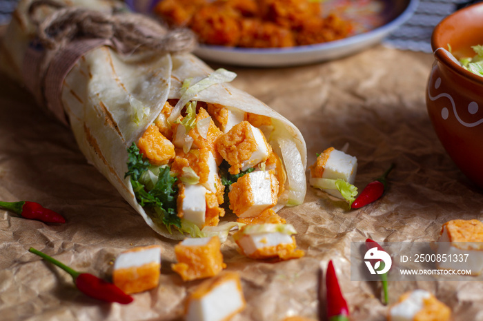 Fresh paneer roll with fresh tomatos, salad, cheese and onions isolated on bright blue background. Side view.selective focus