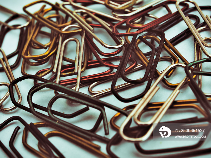 Colorful paperclips on light blue background. Old photo effect.