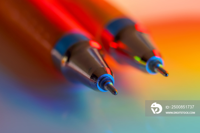 Two ball point pens under colorful lighting effects