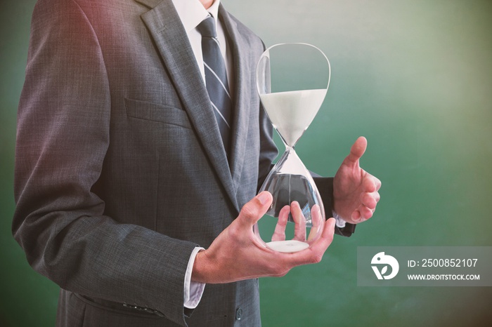 Composite image of mid section of businessman holding hourglass