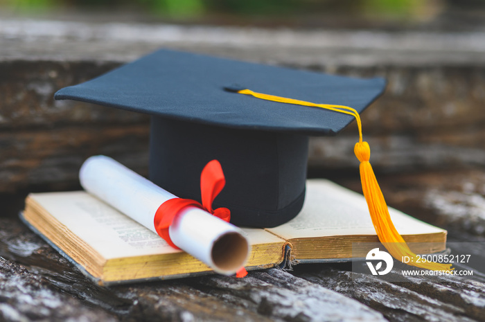 Black graduates hat and yellow tassel place an old book