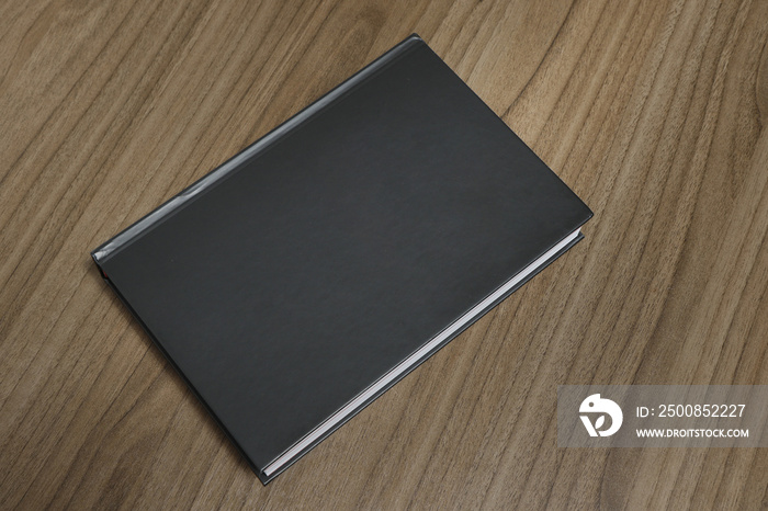 Black hardcover book on wooden surface - mock-up black book