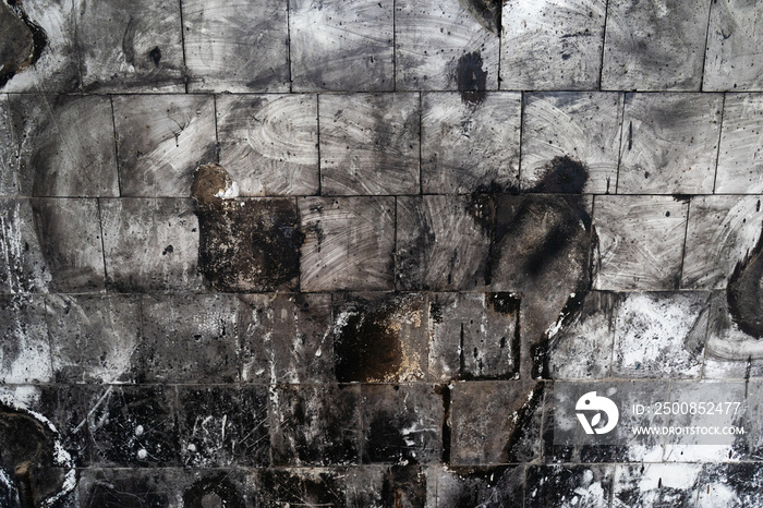 Monochrome spotted tiled wall after fire. Abstract grunge background. High quality photo.