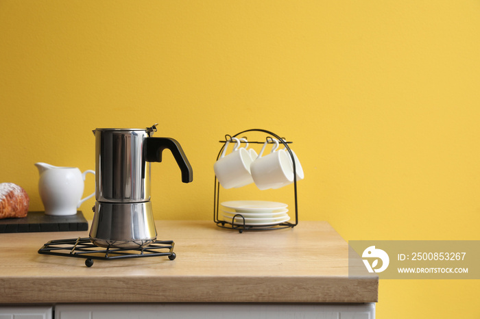 Grid with geyser coffee maker on kitchen counter near yellow wall