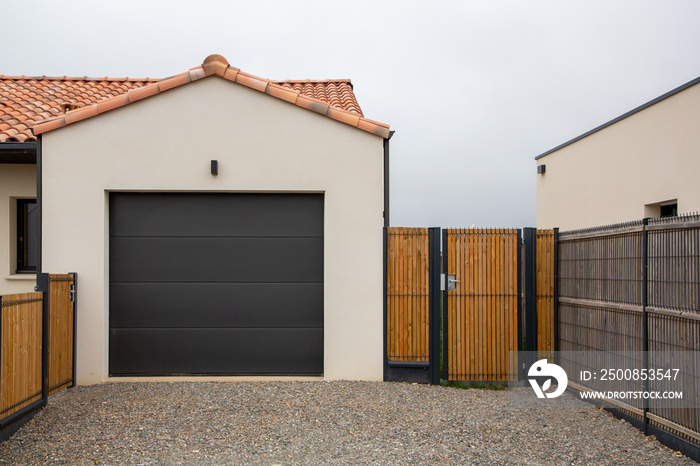 sectional tilting black garage door and entrance gate of modern new house