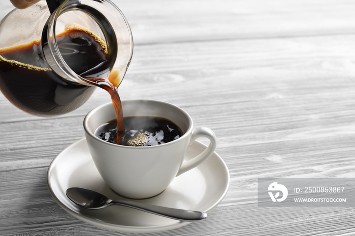 Pouring coffee with smoke on a cup on wooden background