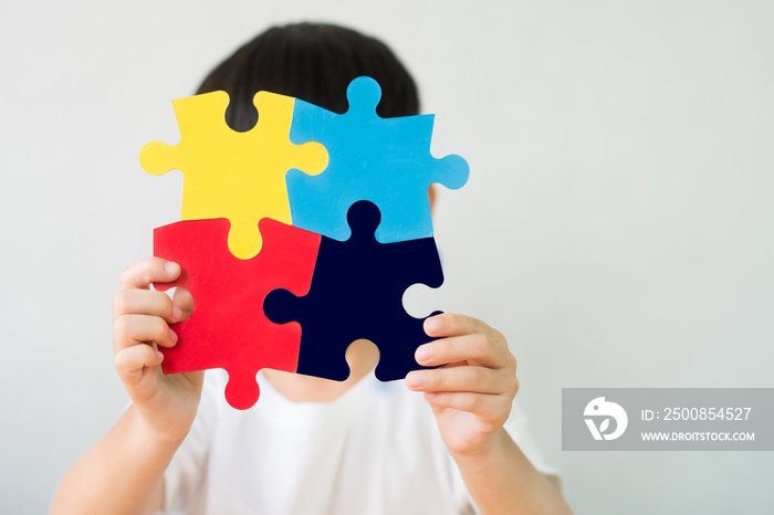 Close up studio portrait : A little child holding a puzzle symbol of Public awareness for autism spectrum disorder. World Autism Awareness Day, Caring, Speak out, Campaign, Togetherness. Isolated.