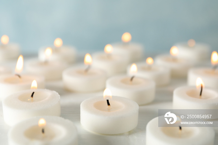 Group of burning candles against blue background, close up