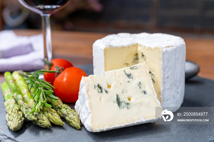 French cheeses collection, piece of Le Bleu cow milk soft blue cheese with white mold.