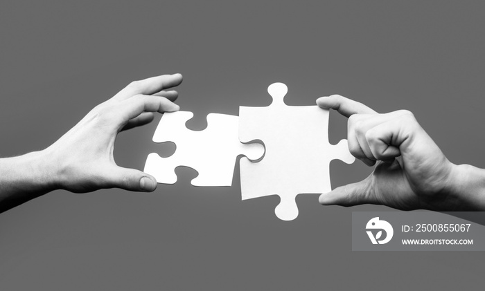 Closeup hands of man connecting jigsaw puzzle. Business solutions, success and strategy concept. Two hands trying to connect couple puzzle. Businessman hand connecting jigsaw puzzle. Black and white