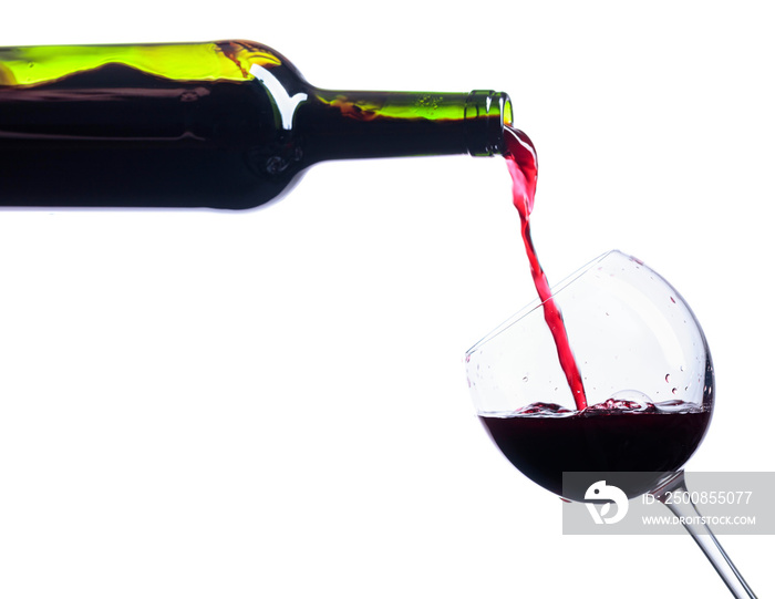 Pouring red wine from bottle to glass isolated on white.