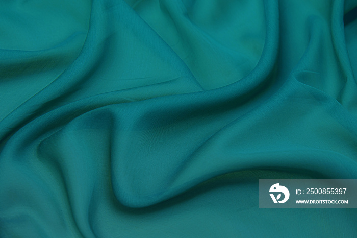 Texture, background, pattern. Texture of green silk fabric. Beautiful emerald green soft silk fabric.