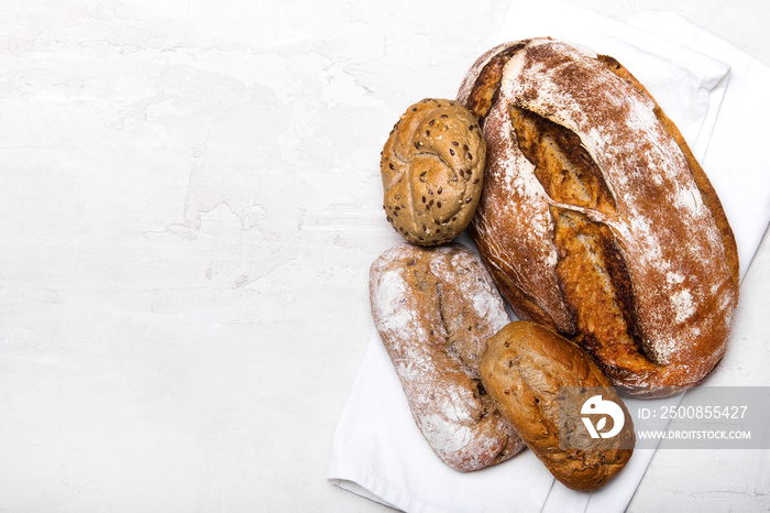 Tasty dark bread and buns  on white background, copy space. Bakery products, wholemeal bread and brown whole wheat buns