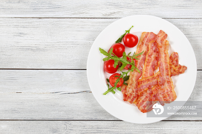 fried bacon, tomatoes, arugula on plate