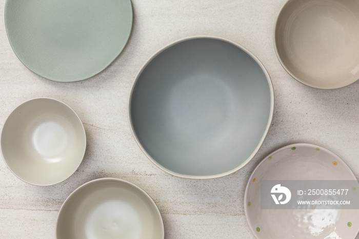 Group of empty blank ceramic round bowls and plates on white stone blackground, Top view of traditional handcrafted kitchenware concept