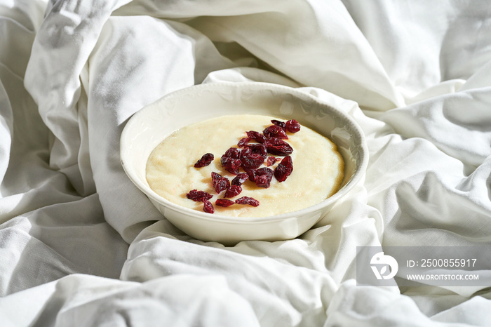 Semolina porridge with berries in a plate on a white sheet. Hard light.