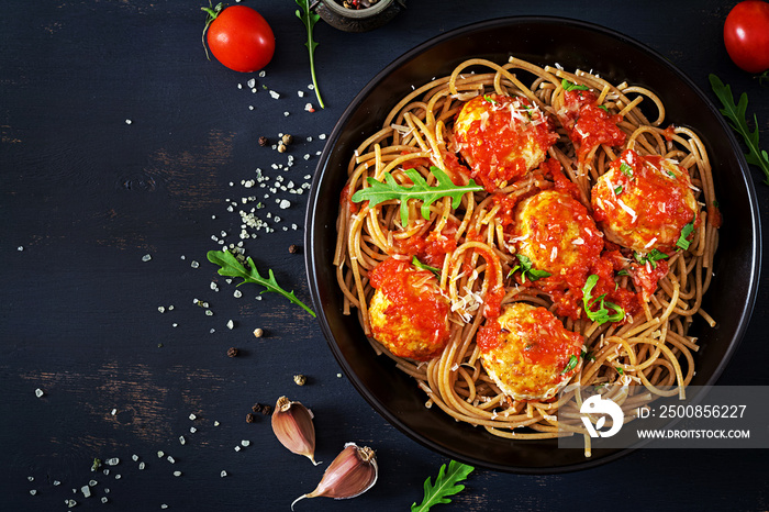 Italian pasta. Spaghetti with meatballs and parmesan cheese in black plate on dark rustic wood background.  Dinner. Top view. Slow food concept