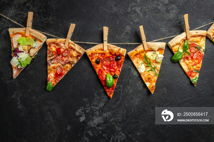 Different pieces of pizza on a string with clothespins dark background. Long banner format. top view