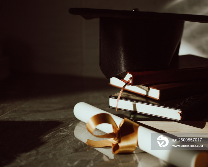 Birrete con libros apilados y diploma al lado. Concepto de graduación.