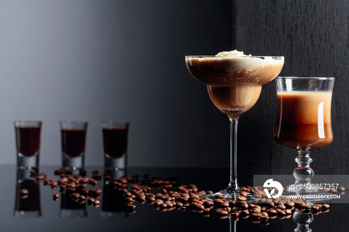 Coffee cocktails and coffee liquor on black reflective background.