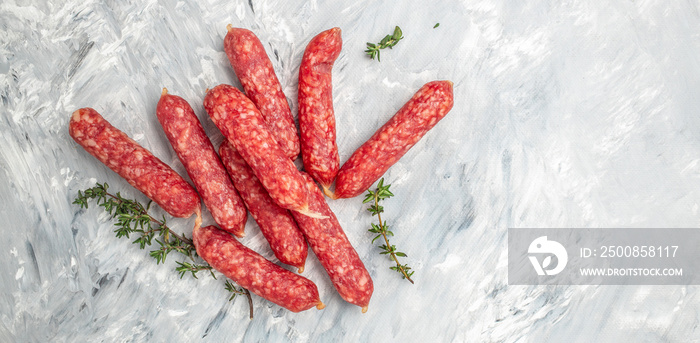 small dty Salami sausages on a light background. Long banner format. top view