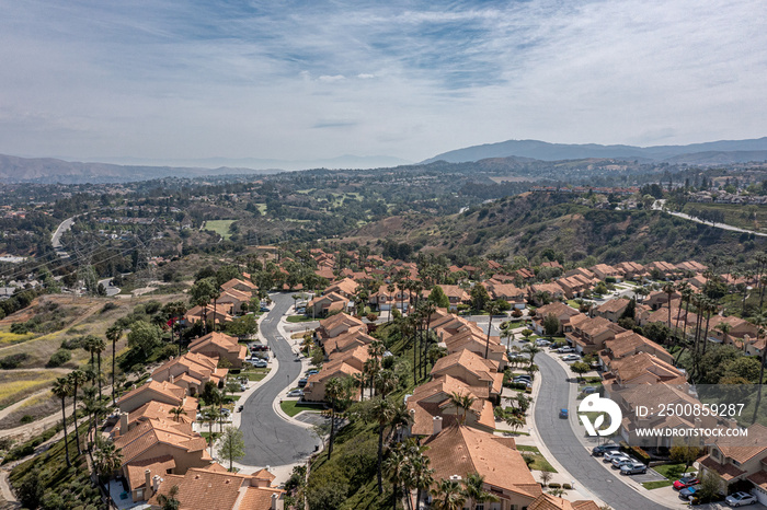 Aerial view of a suburban southern California community in the hills.  Sunny day with silky clouds