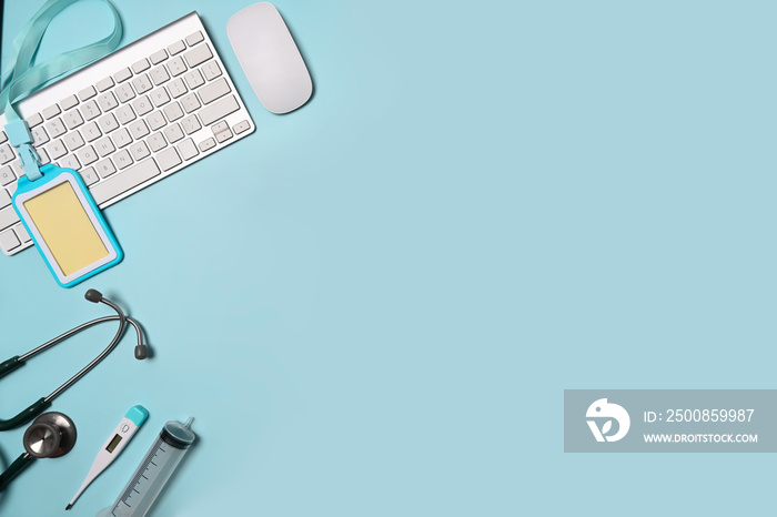 Stethoscope, keyboard and empty badge on blue background. Doctor workspace.