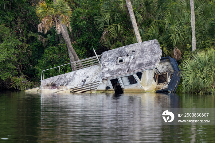 Distroyed Flat bottom barge style boat rests on its side, damaged by hurricane