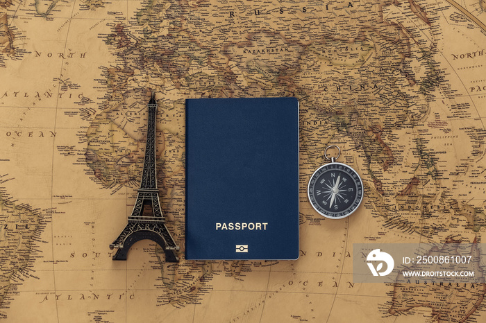 Travel planning. Eiffel tower figurine, compass and passport on old map. Adventure concept