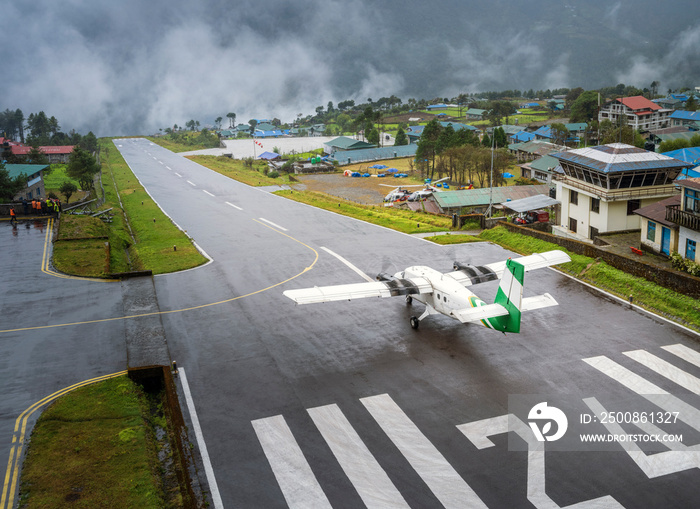 little airplane of local airlines of Nepal on the shortest runway in small airport in village Lukla before take off