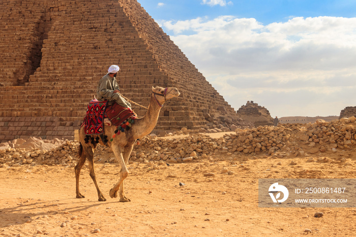 Bedouin riding camel near Great Pyramids of Giza in Cairo, Egypt