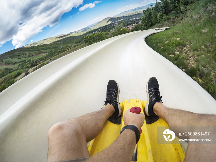 Point of view photo of a man riding down an downhill alpine slide on a fun summer vacation in the mountains