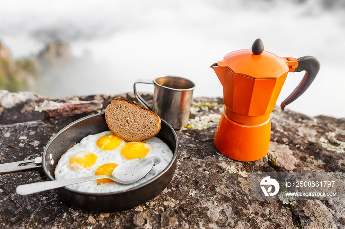 breakfast meal Fried eggs in pan and coffee geyser maker outdoors in mountains, camping food concept