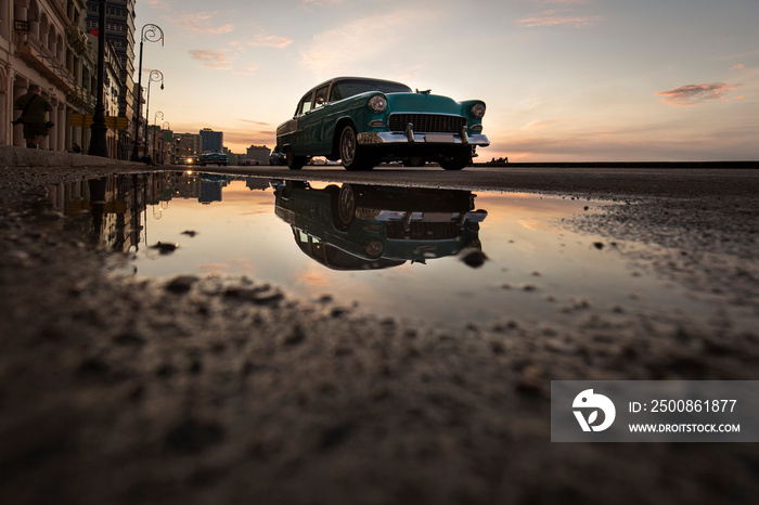 Old car on Malecon street of Havana with colourful sunset in background. Cuba