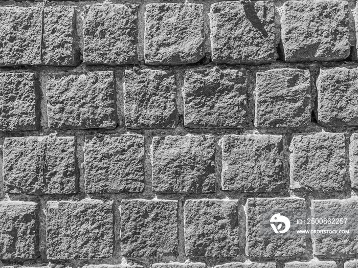 Wall texture of gray stone blocks in daylight.